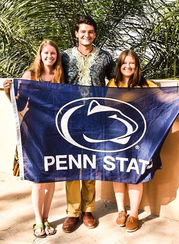 Katie Fiorillo standing with two students holding a Penn State flag.