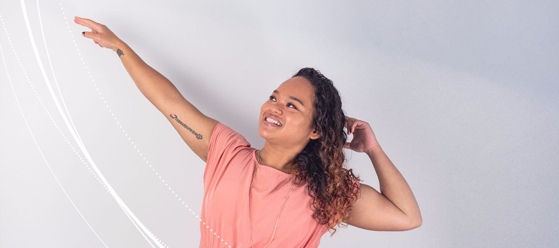 Penn State student Jacquiline Cana pointing upwards while agains a white background.