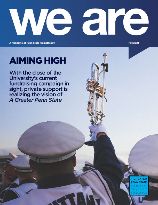 Penn State Blue Band member holding trumpet in the sky.